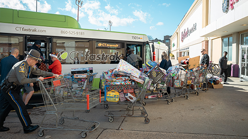 Organizers bring shopping carts full of toys to a CTfastrak bus as donations.